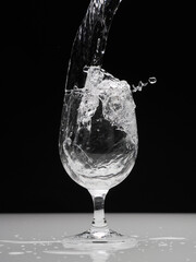 Glass with splashing water on black