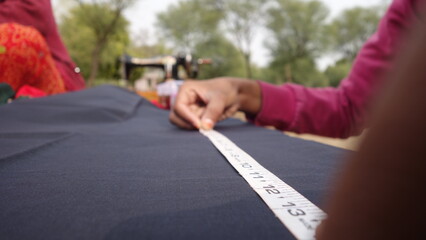 Young Girl measuring on the clothes with plastic strip. Woman tailor working on new clothing. Rajasthan,  India - 4 January, 2020;
