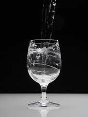 Glass with splashing water on black
