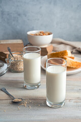 Milk in glasses, oatmeal and bread flakes on a gray background. Side view. The concept of dairy products.