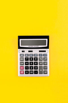 Large silver calculator with black buttons on yellow background with copy space. Conceptual photo of calculation, counting, accounting, computing, profit, loss, tax. Business card. Digital stationery