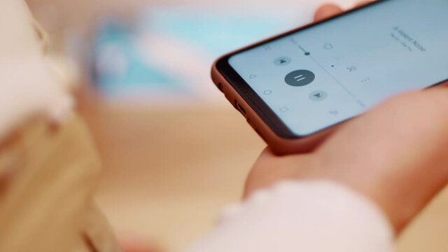 Women picks up her phone to play music on her bluetooth headphones