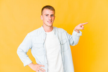 Young caucasian handsome man smiling cheerfully pointing with forefinger away.