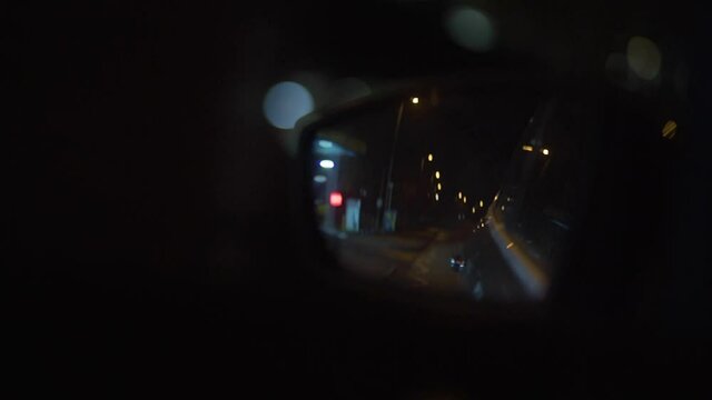 Car driving at night with view through the wing mirror