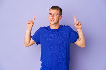Young caucasian handsome man indicates with both fore fingers up showing a blank space.