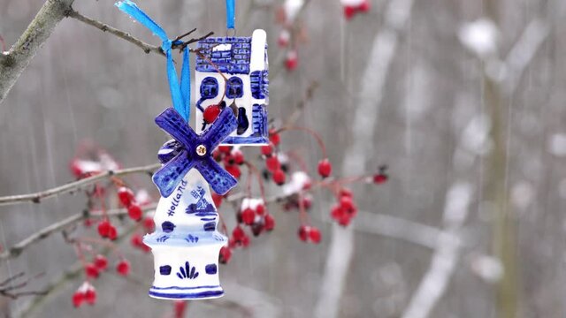 Blue ceramic Christmas toy bought in Amsterdam hangs on a branch