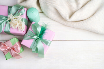 Festive background with gift boxes, candles and a sweater on a white wooden background. Top view, with space to copy. The concept of March 8, spring.