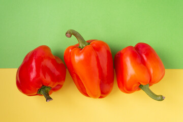 Red sweet peppers on a green and yellow background. View from above. Close-up.