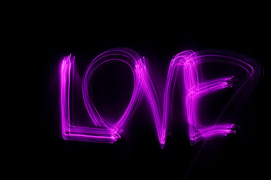 'Love' word written in pink light on black background. Long exposure 
neon light photograph. February 14 Valentine's Day concept. Neon wallpaper.