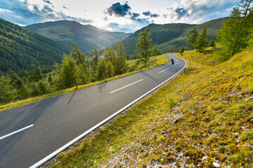 Motorbiker riding in Austrian Alps in beautiful sunset dramatic sky. Travel and freedom, outdoor activities