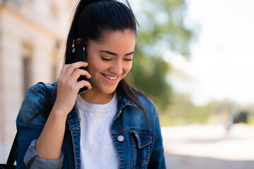 Young woman talking on the phone outdoors.