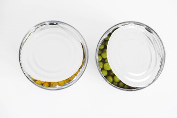 Two open cans with corn and peas on a white background. Top view. Copy, empty space for text