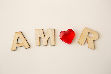 wooden letters with the word "amor" written on white background and red heart