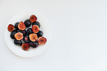 Ripe and sweet figs cut and arranged in a plate on a white background with free space. Fruits and vegetarianism