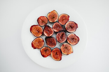 Ripe and sweet figs cut and arranged in a plate on a white background with free space. Fruits and vegetarianism