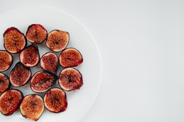 Ripe and sweet figs cut and arranged in a plate on a white background with free space. Fruits and vegetarianism