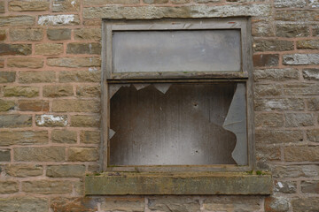 Rotted wooden window frame with broken window