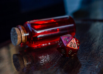 Marbled red 20 sided dice in front of a potion on a wet wooden surface