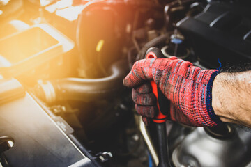 Mechanic wears red cloth gloves to repair a car's engine