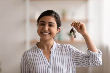 House of dream. Headshot portrait of excited indian female happy winner buyer renter tenant of new home apartment. Young mixed race woman proud homeowner looking at camera showing keys of modern flat