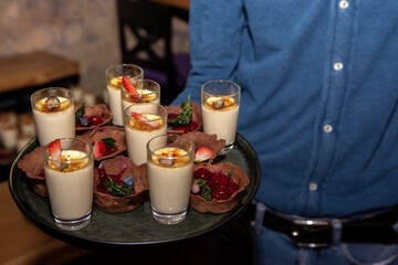 a young guy holds alcoholic beverages in glasses on a tray. Concept of celebration, banquet. Selective focus