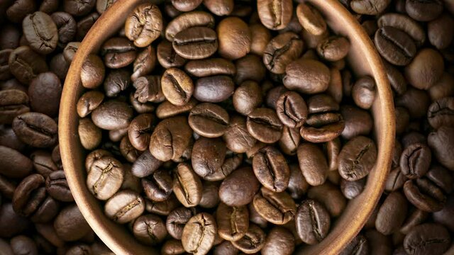 Roasted coffee beans in a brown bowl rotates. Seamless food concept animation background