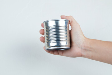 Hand holding a tin can of boiled sweet corn on a white background