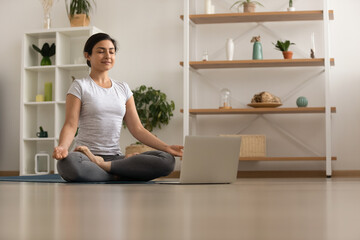 Serene millennial mixed race woman engaged in yoga practice breath deep feel comfort harmony....