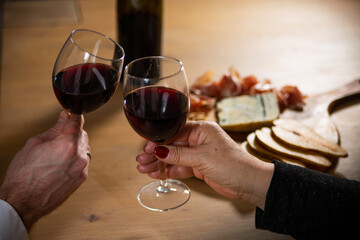 Making a toast by clinking two glasses with red wine.
