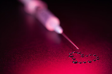 The tip of the syringe with a drop, drops in the shape of a heart