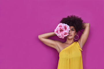 Woman with afro hair. She has a yellow dress and behind is a purple background