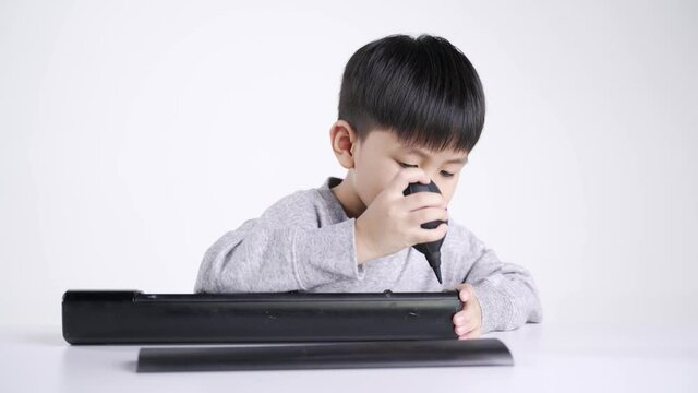 Asian boy about 5 years old using rubber bulb air pump dust blower for cleaning the electronic speaker