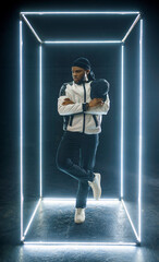 Rapper posing in illuminated cube, dark background