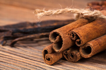 Stack of cinnamon sticks with vanilla beans on a wooden background. Macro photography of spices.