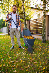  Autumn garden works, collecting autumn leaves with rake and a plastic container.