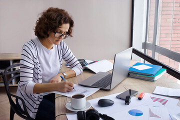 Fototapeta premium Empty space for text. Female accountant is working from home.