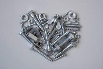 Silver screws, bolts and nuts in heart shape. Valentines Day greeting card for a man, boyfriend or husband. Heart of steel. Robot's emotions and feelings. Fathers Day card or banner.