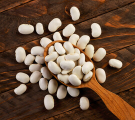 Fototapeta na wymiar White beans in a spoon on a wooden background. The view from top