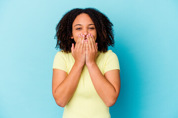 Young african american mixed race woman isolated laughing about something, covering mouth with hands.