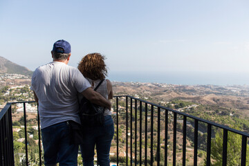 Fototapeta na wymiar Fotografía de una pareja mirando el paisaje con el mar de fondo.