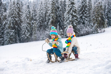 Children on a wooden sled on a winter day. Active winter kids outdoors games.