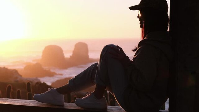 Beautiful sunset, with female model looking at the horizon with her marked silhouette, looking at pichilemu, punta de lobos, surf beach