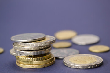 Stack of coins from different countries on a purple background