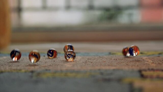 Slow motion footage showing marbles bouncing to a carpet. Selective focus.
