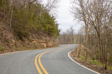 Fototapeta premium Wavy road in mountains between trees under sky