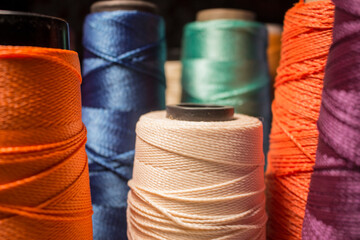 Multiple colored spools and line cones. Blue, orange purple, green, white threads.
