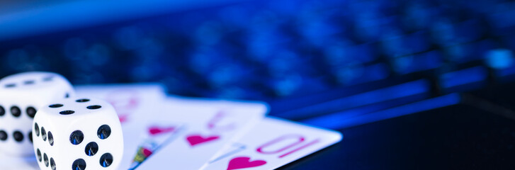 Online gaming platform, casino and gambling business. Cards and dice on laptop keyboard, toned in...