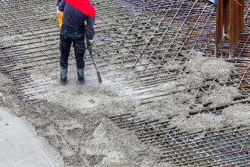 Construction worker using concrete vibrator for compacting concrete - obrazy, fototapety, plakaty