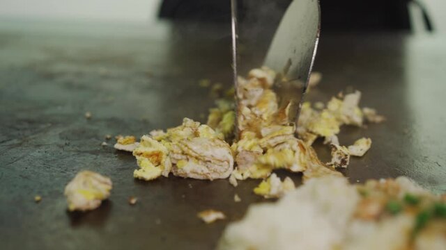 Fried Egg Skillfully Chopped With Laddle On Hot Griddle Plate - close up shot