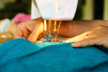 Mujer cosiendo con maquina de cocer eléctrica. Manos de mujer haciendo manualidades de costura 